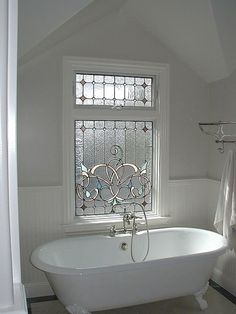 a white bath tub sitting under a window in a bathroom