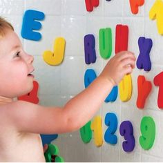 a little boy that is playing with magnets on the wall in front of him