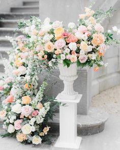 an arrangement of flowers in a vase on a pedestal next to some stairs and steps