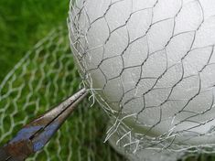 a pair of pliers cutting through the wire on top of a large white ball