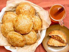 several pastries on a plate next to a cup of tea and some cinnamon sticks