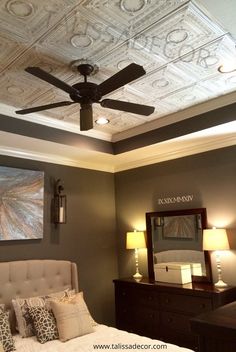 a bed room with a neatly made bed and a ceiling fan in the middle of it