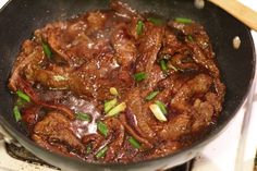 beef and onions cooking in a wok on the stove