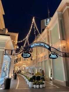 the entrance to a shopping mall at night with lights strung from it's sides