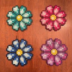 four pieces of perler bead art on a wooden table