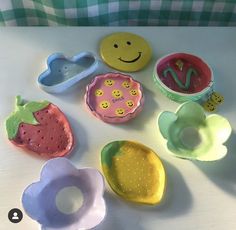 there are many plastic bowls and spoons on the table with smiley faces painted on them