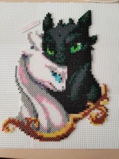 a cross stitch picture of two black cats