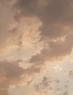 an airplane is flying high in the sky with clouds behind it and sun peeking through