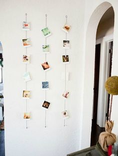 there are many pictures hanging on the wall with clothes pins attached to them, along with other things