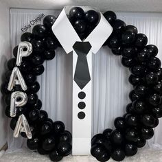 black and white balloons are arranged around a man's tie in the shape of a wreath