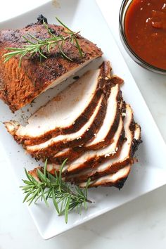 sliced meat on a plate with sauce and herbs