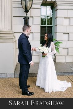 a bride and groom standing in front of a white building holding hands with each other