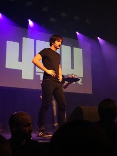 a man standing on stage holding a skateboard