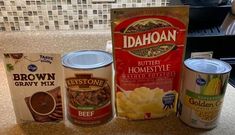 three cans of food sitting on top of a counter next to a package of brown gravy