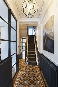 a staircase leading up to the second floor in a building with an ornate carpeted stair case and chandelier