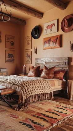 a bed sitting in a bedroom next to a wall with pictures on it and cowboy hats hanging above