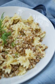 a white plate topped with pasta and meat covered in sauce next to a blue napkin