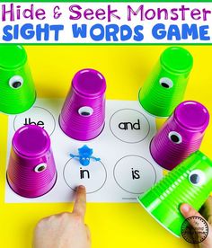 a hand is pointing at the sight words game on a yellow background with green and purple cups