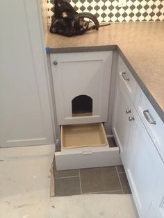 a dog house built into the side of a kitchen counter with a cat in it