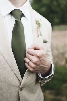 a close up of a person wearing a suit and tie with a boutonniere