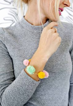 a woman wearing a bracelet with pom poms on it