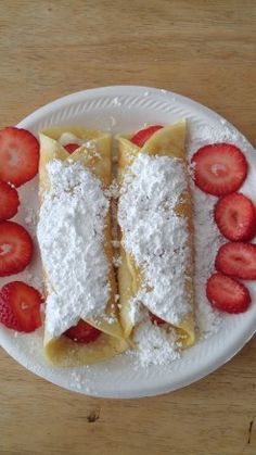 two pastries with powdered sugar and strawberries on a plate