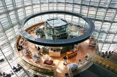 the inside of an office building with glass walls and lots of people standing in it