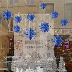 blue and white snowflakes are hanging from the glass window in front of a store