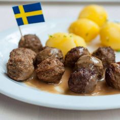 some meatballs and potatoes on a white plate with a flag sticking out of it