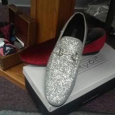 a pair of silver shoes sitting on top of a shoe box next to other items