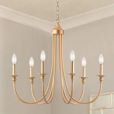 a gold chandelier hanging from the ceiling in a room with beige walls and white trim