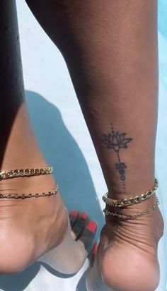 a woman's foot with a cross tattoo on her left ankle and gold chain around the ankles