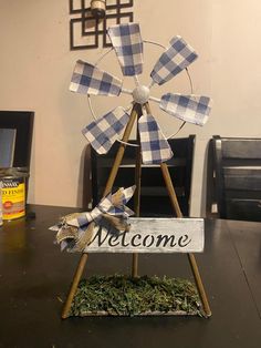 a welcome sign with a windmill on it sitting on top of a wooden table in front of a wall