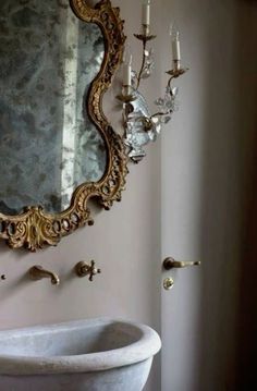 a bathroom with a sink, mirror and chandelier hanging on the wall above it