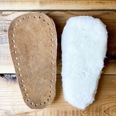 a pair of sheepskin slippers on top of a wooden floor next to each other