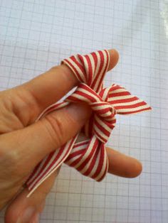 a hand holding a red and white striped bow