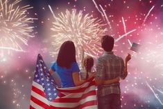 two people holding an american flag and fireworks