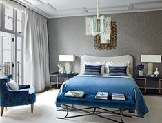 a bedroom with blue and white bedding, two chairs and a chandelier