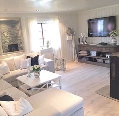 a living room filled with white furniture and a flat screen tv mounted on the wall