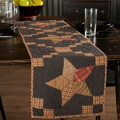 a quilted table runner on top of a wooden table with fruit in the background