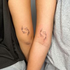 two people with matching tattoos on their arms, one holding the other's arm