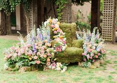 an old chair covered in moss and flowers