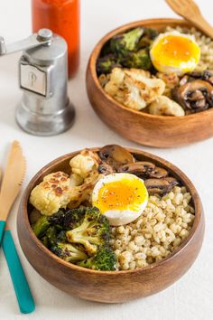 two wooden bowls filled with rice, broccoli and an egg