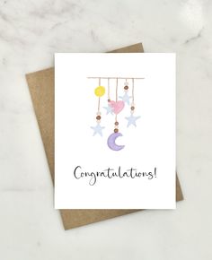 a card with the words congratulations written on it and stars hanging from strings above them