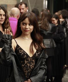 a woman standing in front of a crowd holding her hand up to the camera and smiling