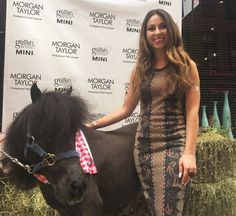 a woman standing next to a horse on top of hay bales in front of a sign