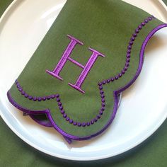 a green and purple napkin with the letter h on it sitting on a white plate