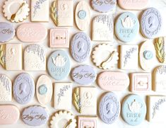 wedding cookies are arranged in pastel colors on a white tablecloth with the names of bride and groom