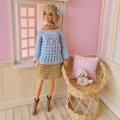 a doll is standing next to a basket with a teddy bear in it and a pink wall behind her