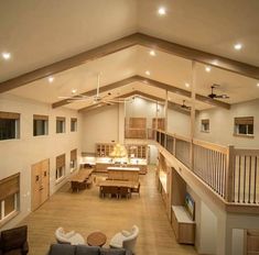 a large open living room and dining area with wood floors, high ceilings, and white walls